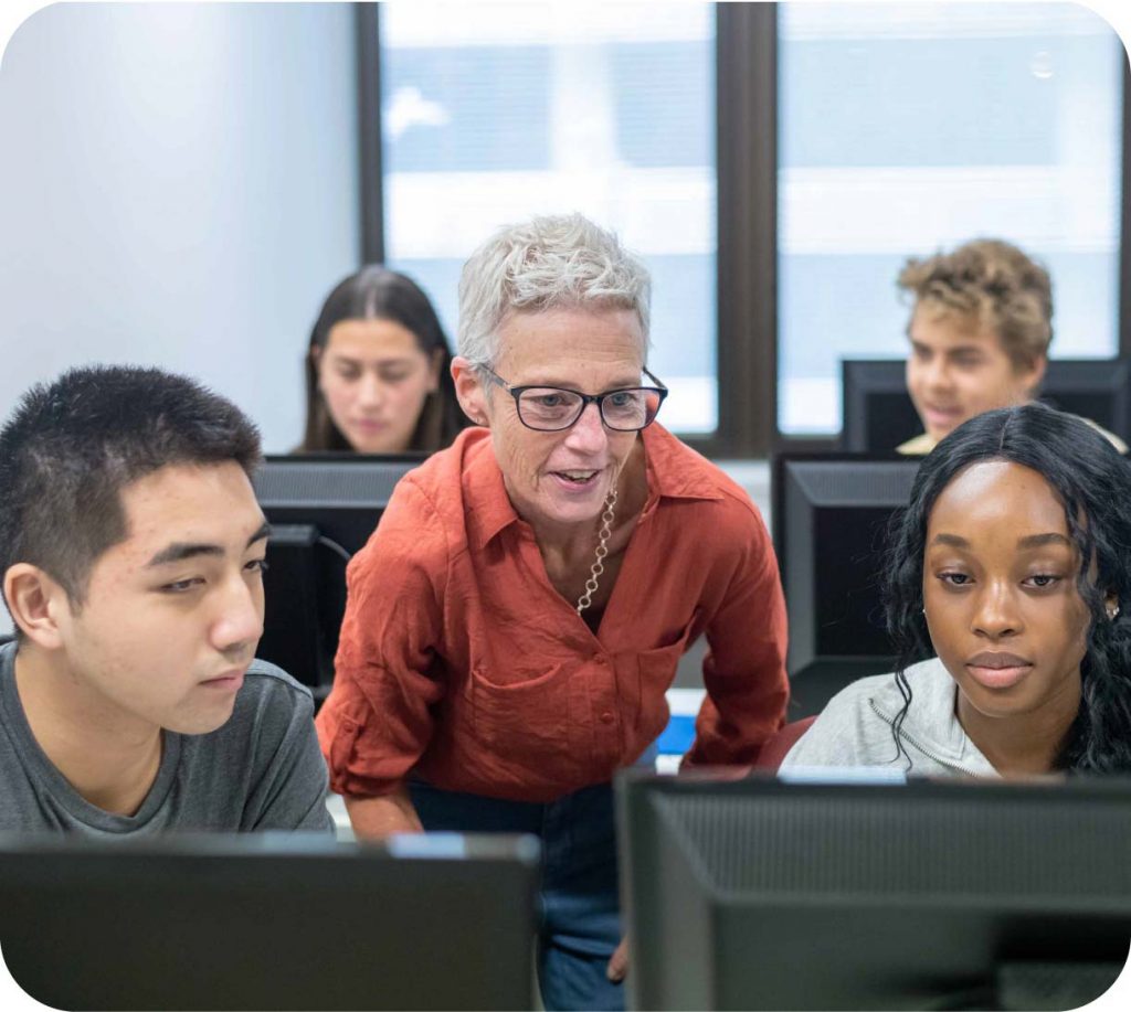 A high school teacher helping students in a computer class