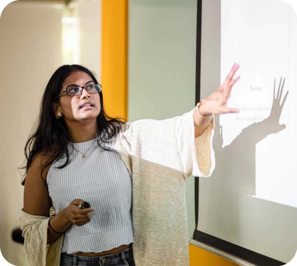 A girl presenting in front of a projector