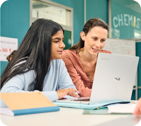 A teacher helping a student on their laptop