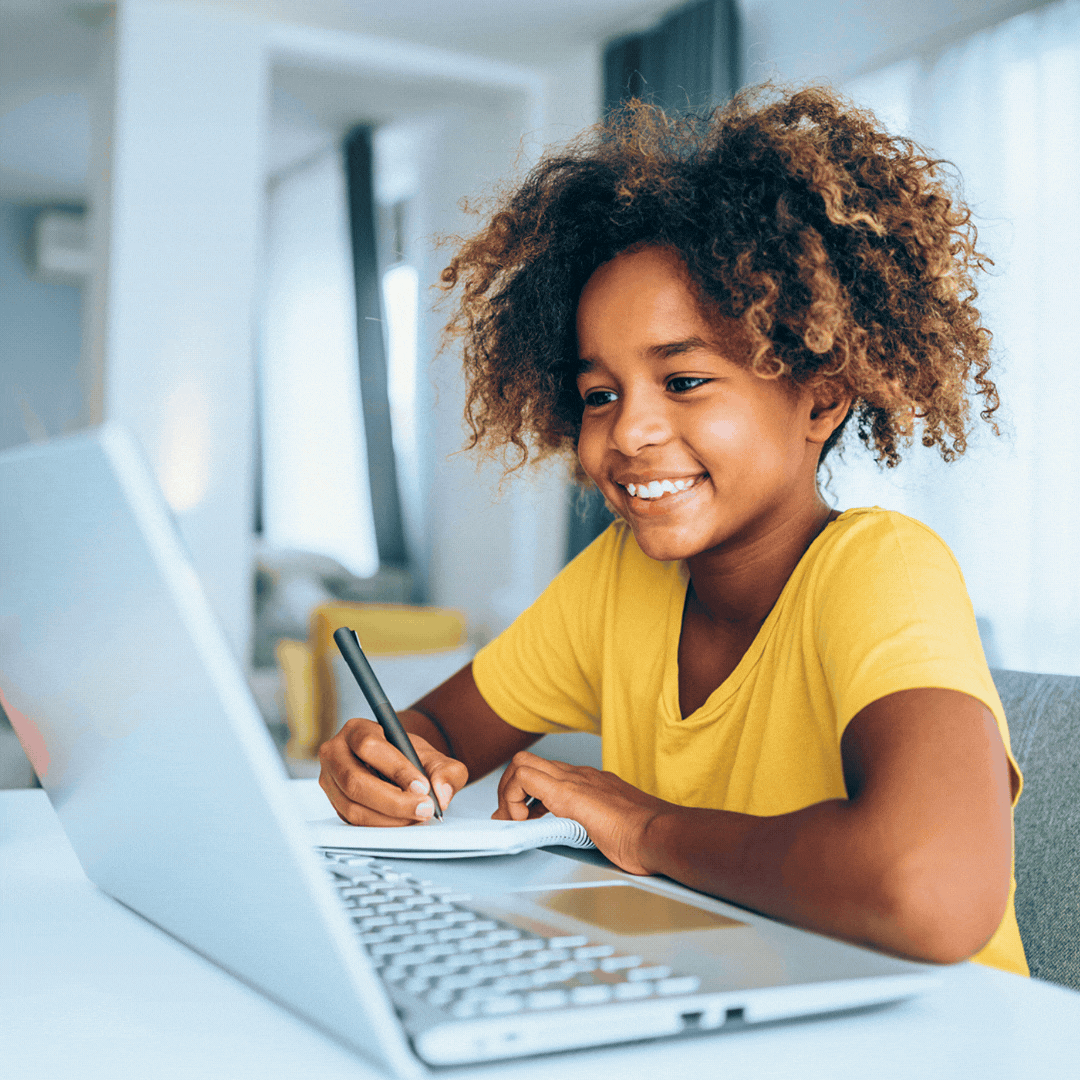 Animated clip of a student smiling while writing in a notebook beside an open laptop at a desk.
