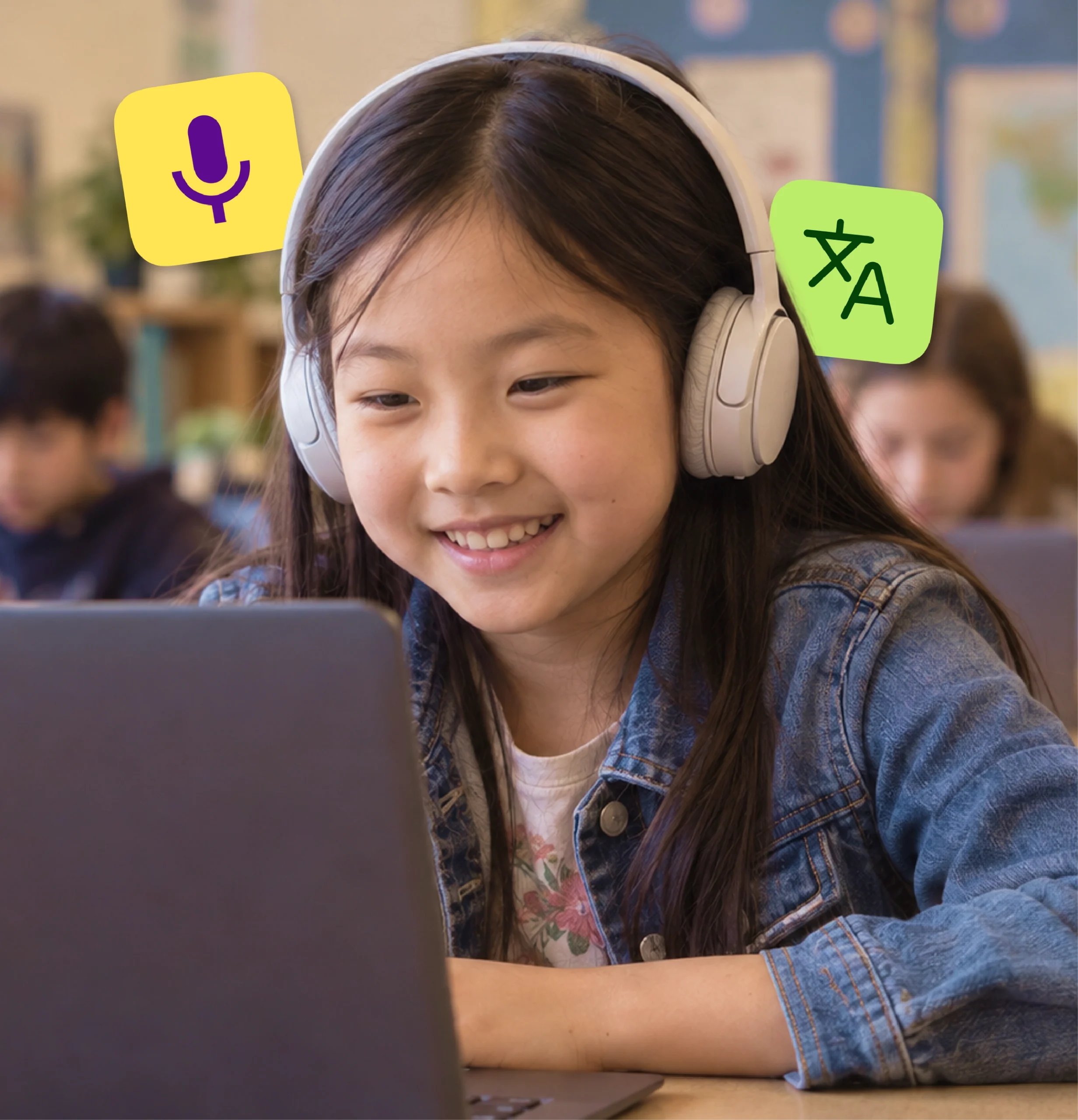 An elementary student in headphones smiles while working on a laptop in class.