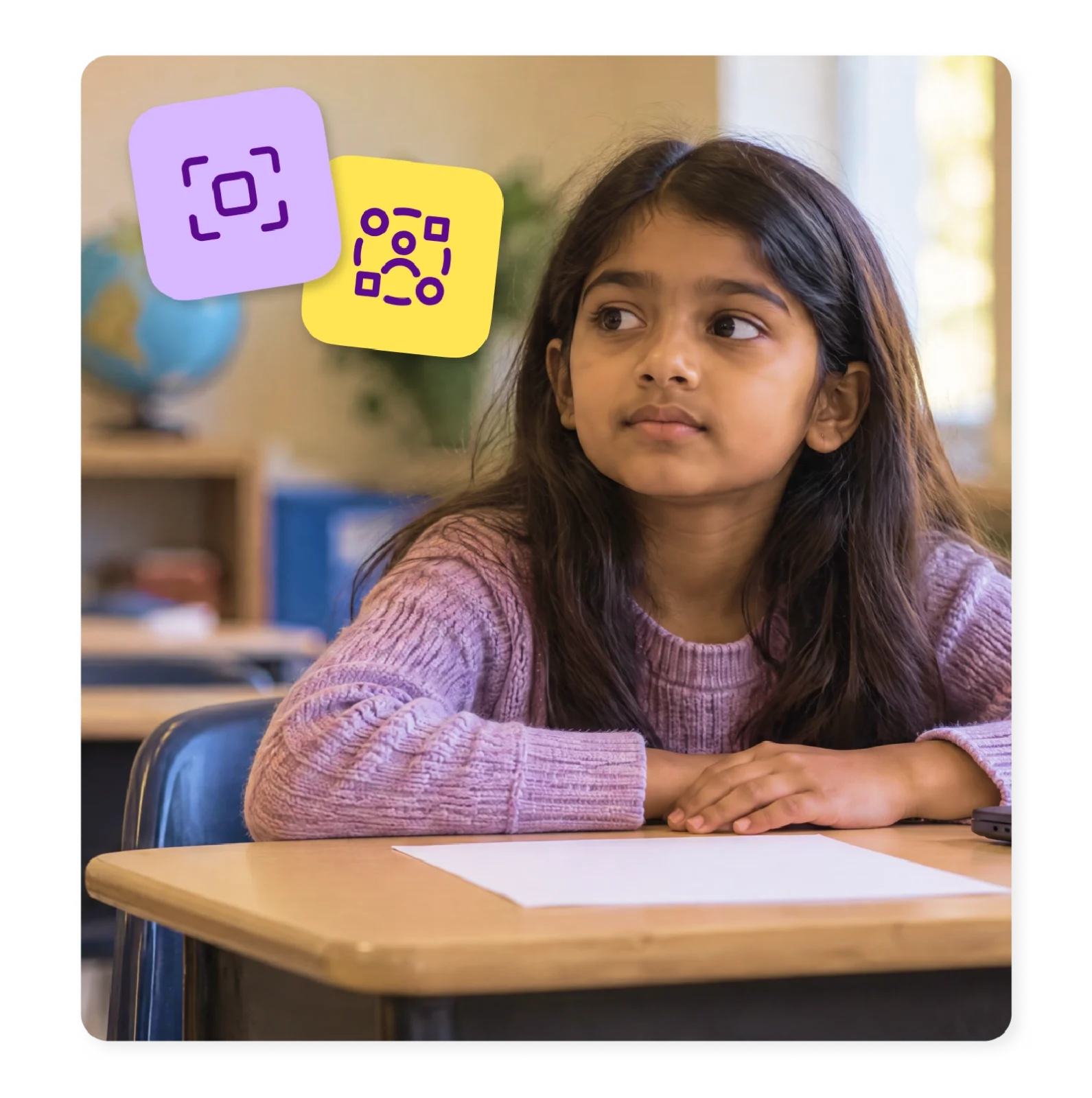 An elementary student sits at her desk beside a blank sheet of paper, gazing off to the side.