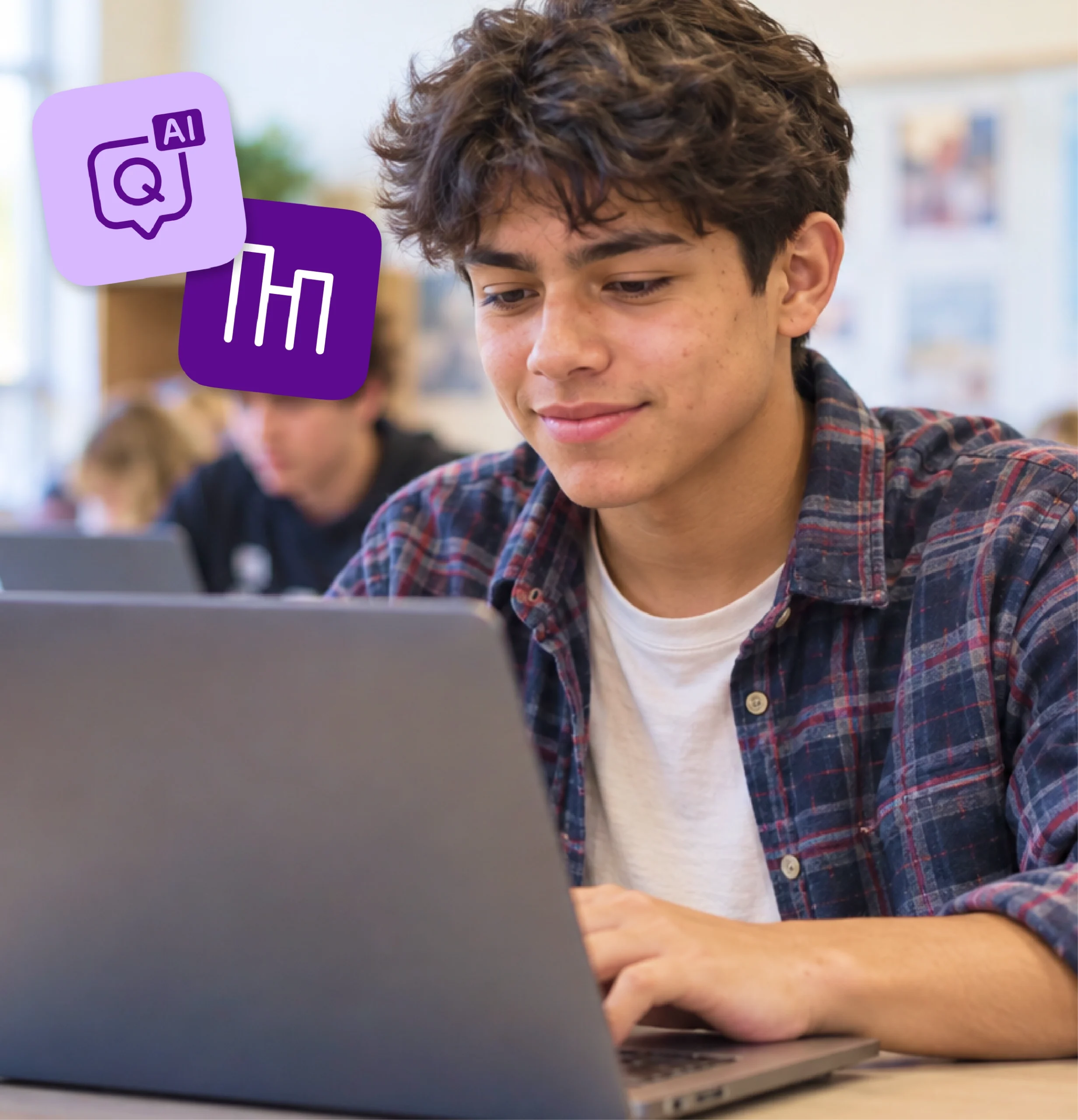 A high school student smiles as he works through an assignment on his laptop.
