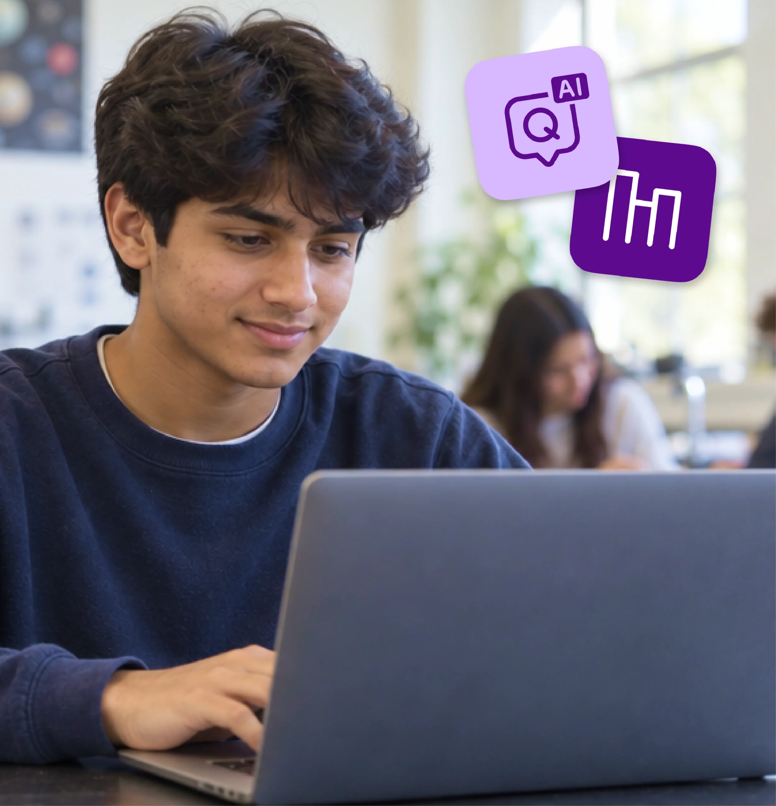 A high school student smiles as he works through an assignment on a laptop.