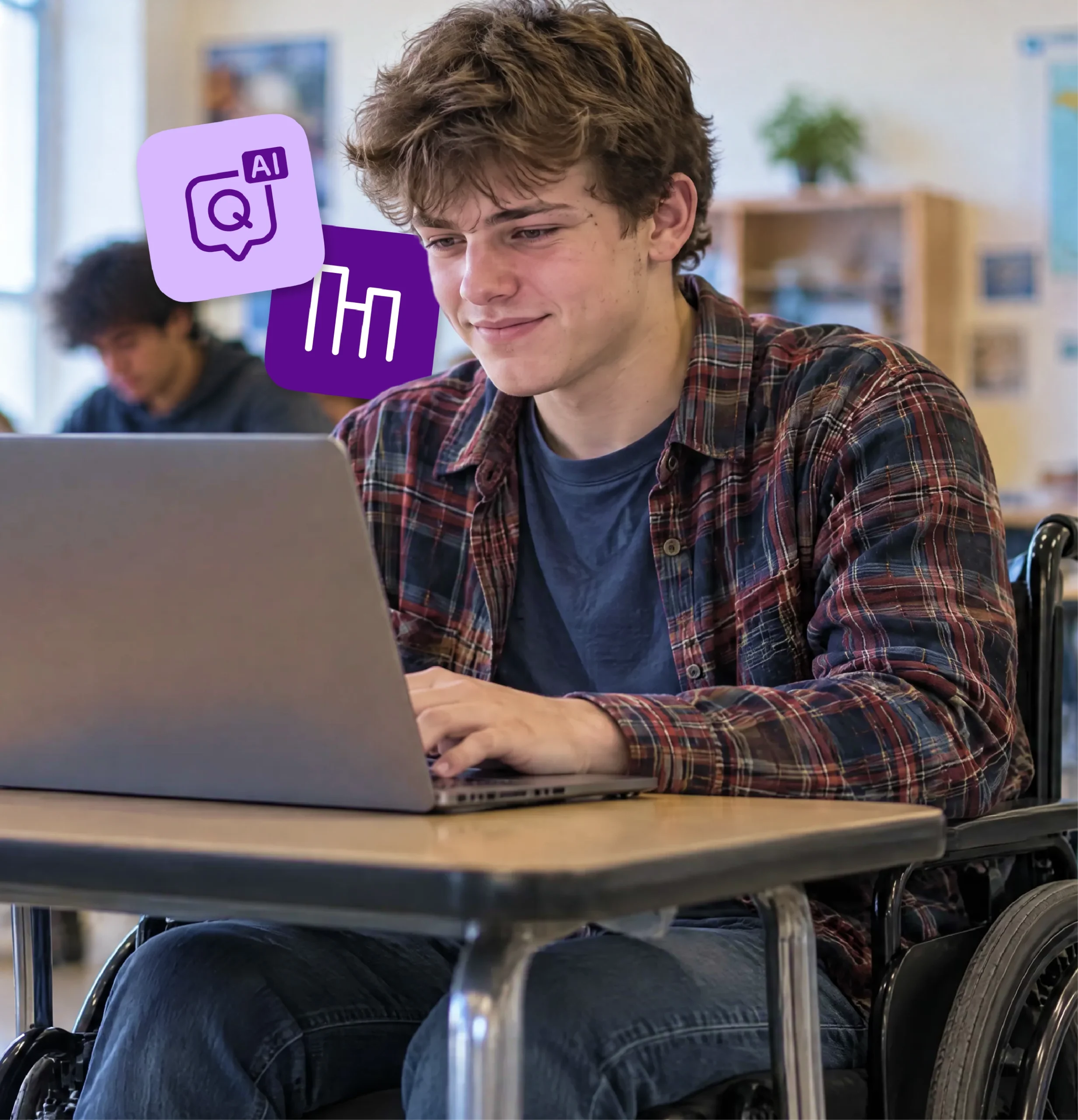 A high school student in a wheelchair smiles as he works on a laptop.